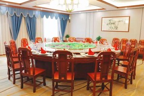 Un salón de conferencias con una mesa redonda, sillas y una araña.