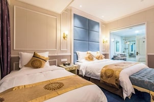 Habitación de hotel con dos camas, un espejo grande y vista al baño.