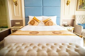 A hotel room with a large bed, a tufted headboard, and a matching ottoman. - Jintian International Hotel (Suqian)