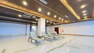 A spacious indoor area with a row of chairs and a tiled floor, likely a waiting area or lobby.