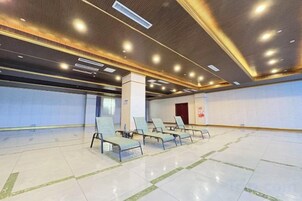 Amplio espacio interior con una fila de sillas y piso de baldosas, probablemente un área de espera o vestíbulo.