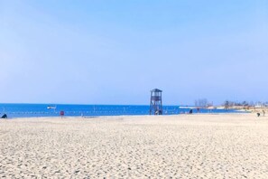 A beach with a lifeguard tower, clear blue sky, and calm sea. - Jintian International Hotel (Suqian)