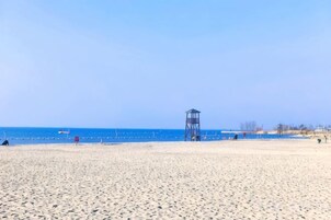 A beach with a lifeguard tower, clear blue sky, and calm sea.
