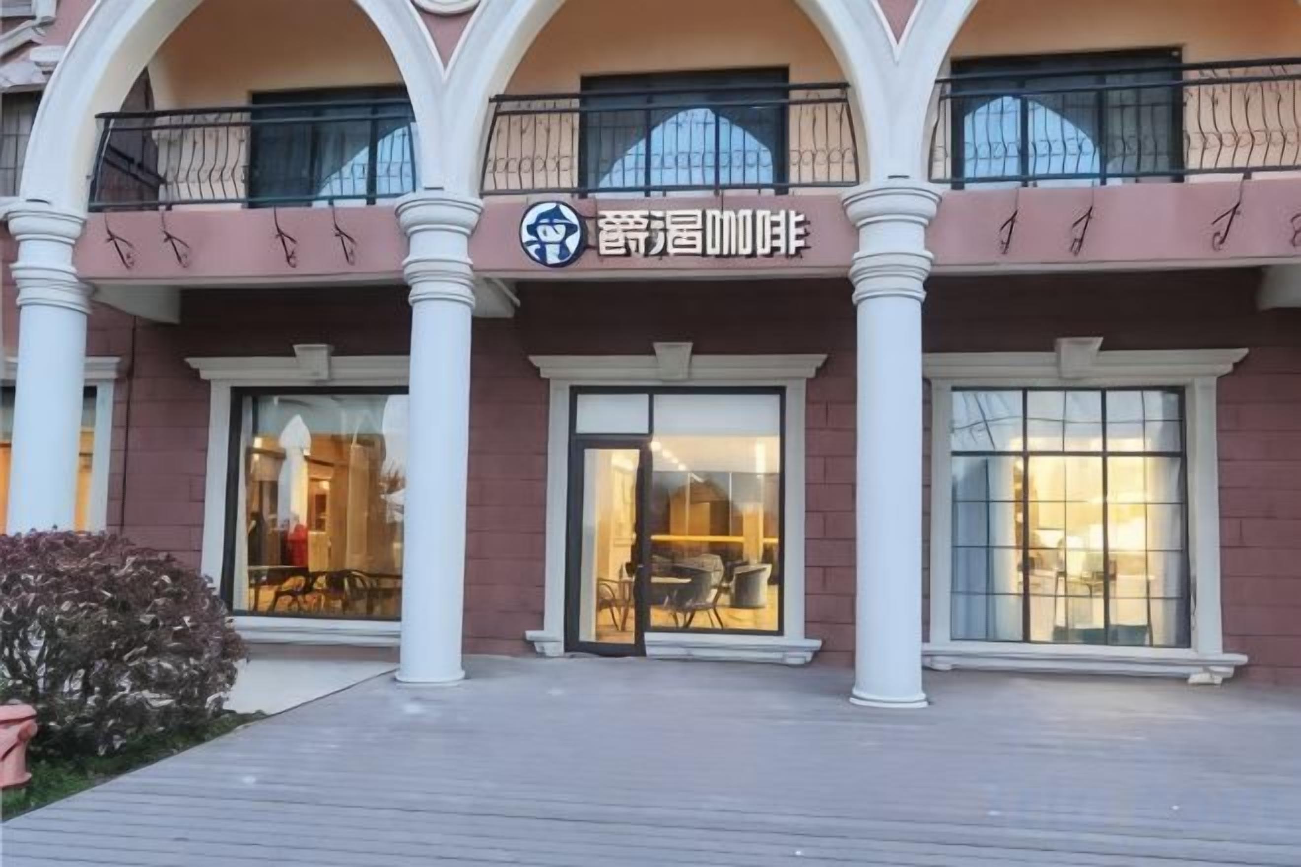 A building with a storefront, large windows, and a balcony with railings.