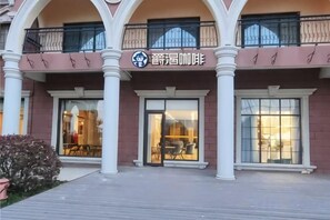 A building with a storefront, large windows, and a balcony with railings. - Jintian International Hotel (Suqian)