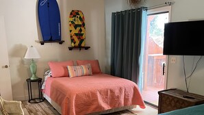 Een slaapkamer met een bed, een stoel, een surfplank en een televisie.