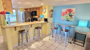 A compact kitchen with a bar area, a dining table, and a sofa in a living area.