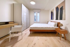 Ein Schlafzimmer mit Bett, Schreibtisch, Stuhl und Fenster.