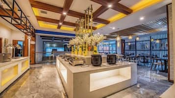 A modern hotel lobby with a reception desk, seating area, and a decorative centerpiece.