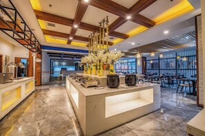 Um saguão de hotel moderno com balcão de recepção, área de estar e peça decorativa.