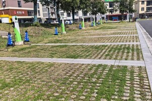 Un sendero pavimentado con césped y losas de piedra que conduce a un edificio con un letrero rojo.