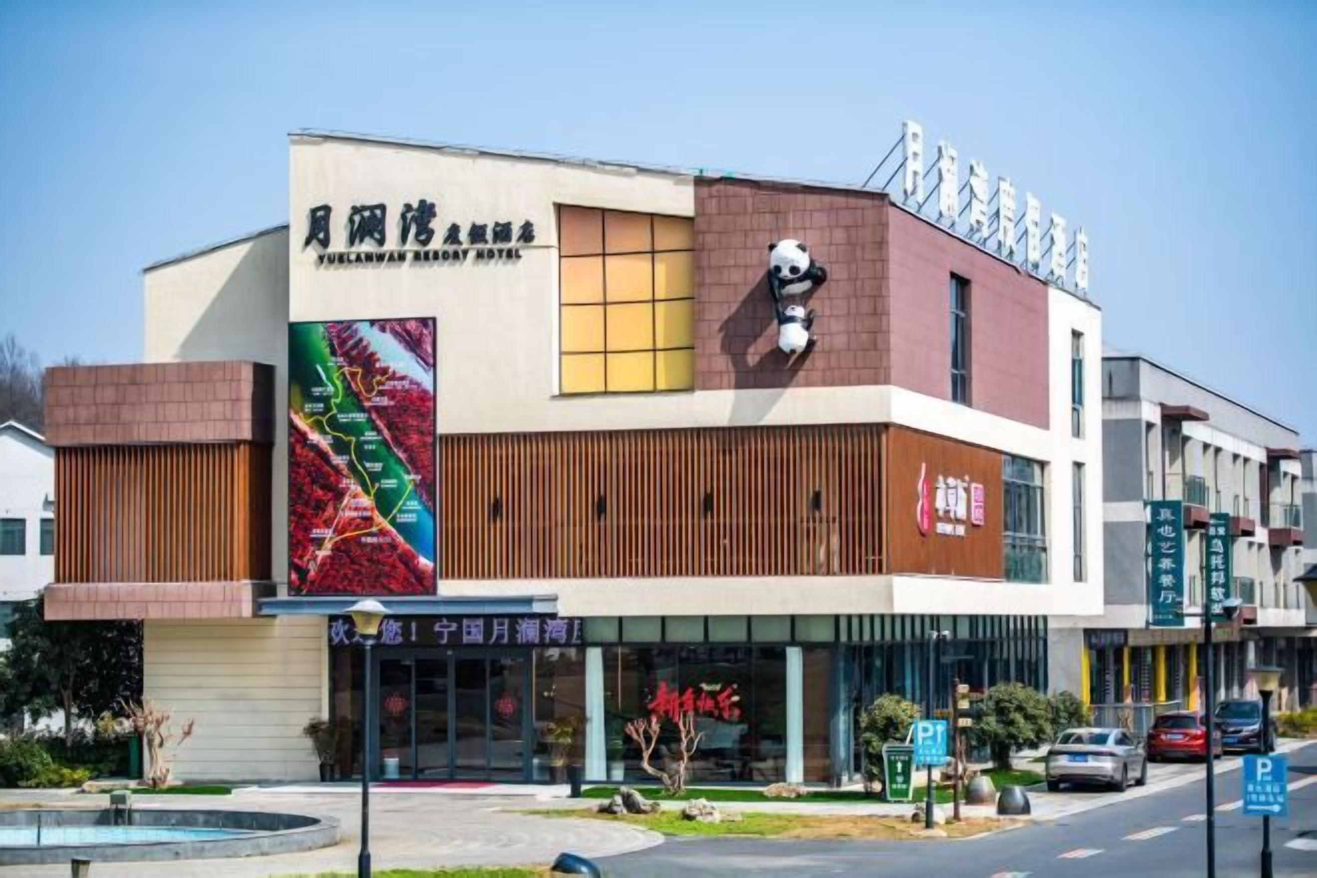 A modern hotel with a prominent sign, a large window display, and a parking area.