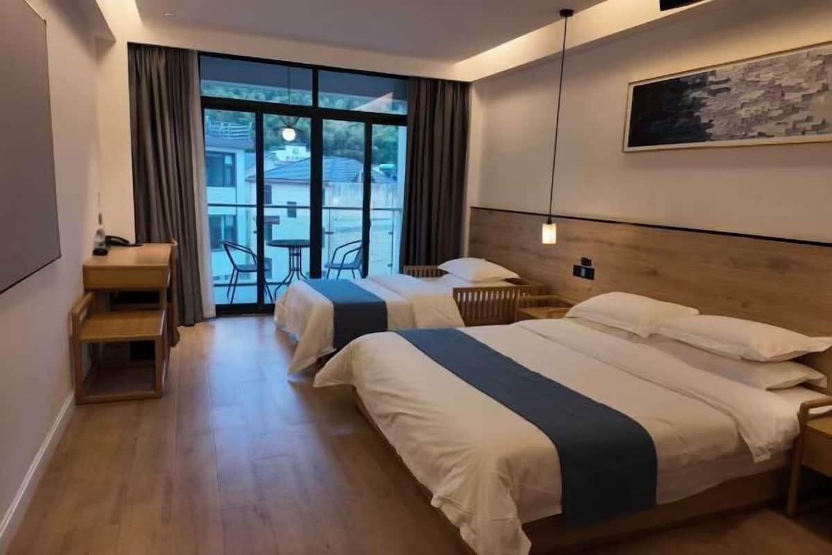 Habitación de hotel con dos camas, un escritorio, una silla y vistas al exterior.