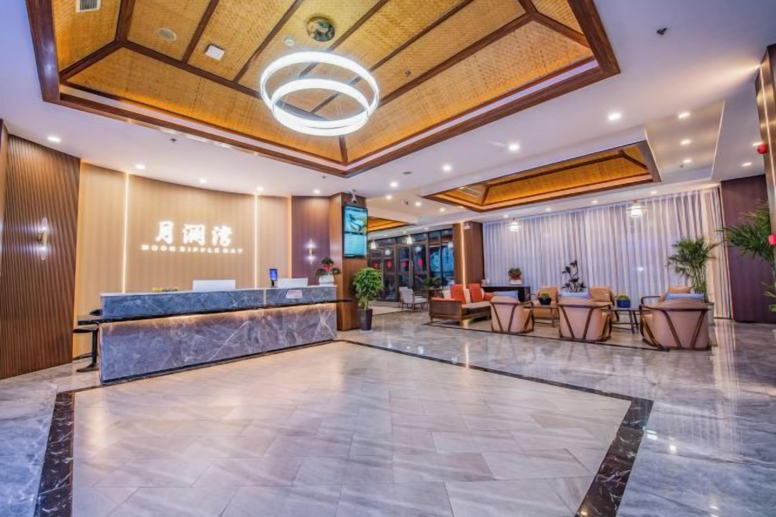 A hotel lobby with a reception desk, seating area, and a large open space.