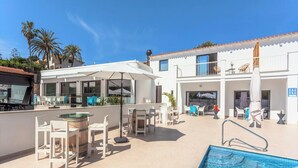 A modern outdoor pool area with a bar, seating, and a covered patio. - MARTA BEACH 2 – 2 minutes from La Fustera Beach (Benissa)