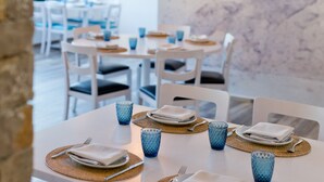 A dining area with tables set for two, each with a placemat, folded napkins, and blue glassware. - MARTA BEACH 2 – 2 minutes from La Fustera Beach (Benissa)