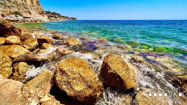 A rocky shoreline with clear blue water and a cliff with vegetation. - MARTA BEACH 2 – 2 minutes from La Fustera Beach (Benissa)