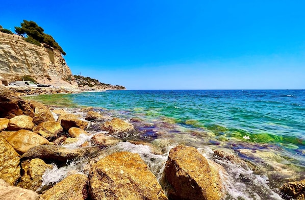 Eine felsige Küstenlinie mit klarem, blauem Wasser und einer Klippe, die mit Vegetation bewachsen ist.