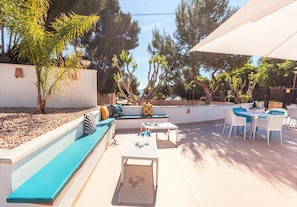 Eine Terrasse im Freien mit Sitzgelegenheiten, Tischen und Sonnenschirmen.