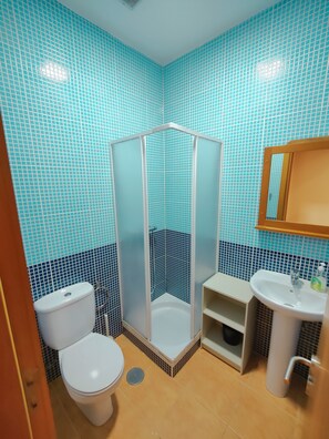 Une salle de bain avec une douche, des toilettes, un lavabo et des murs carrelés.