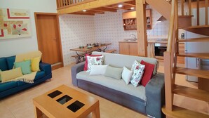 Una sala de estar acogedora con un sofá, una mesa de centro de madera y una escalera que sube a un nivel superior.
