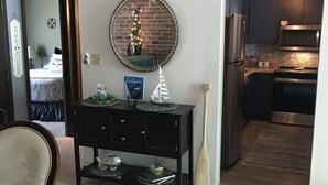 Zona pranzo con tavolo, sedie, un consolle nero con oggetti decorativi, uno specchio e un cartello sopra il consolle.