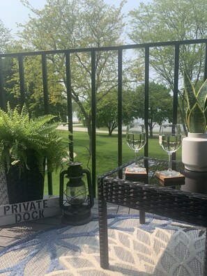 Un muelle privado con una mesa dispuesta para dos, que incluye un vaso de agua, una copa de vino y una planta en maceta.