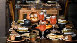 A rustic dining table set with various dishes and drinks, overlooking a scenic outdoor view. - Zai Patacho (Porto de Pedras)
