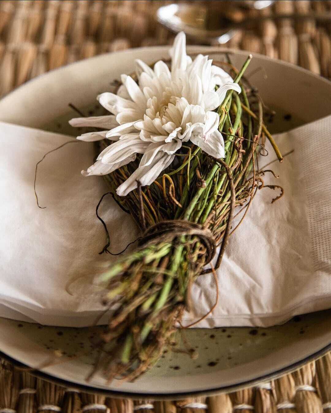 A bouquet of white flowers with green stems and leaves, placed on a white plate with a textured surface.