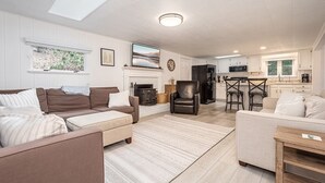 Een moderne woonkamer met een open haard, een keuken en een eethoek.