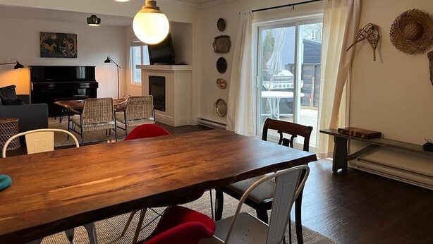 Un comedor con una mesa y sillas de madera, chimenea y vista al exterior a través de un ventanal grande.