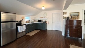 Una cocina con pisos de madera oscura, un refrigerador de acero inoxidable y un microondas.