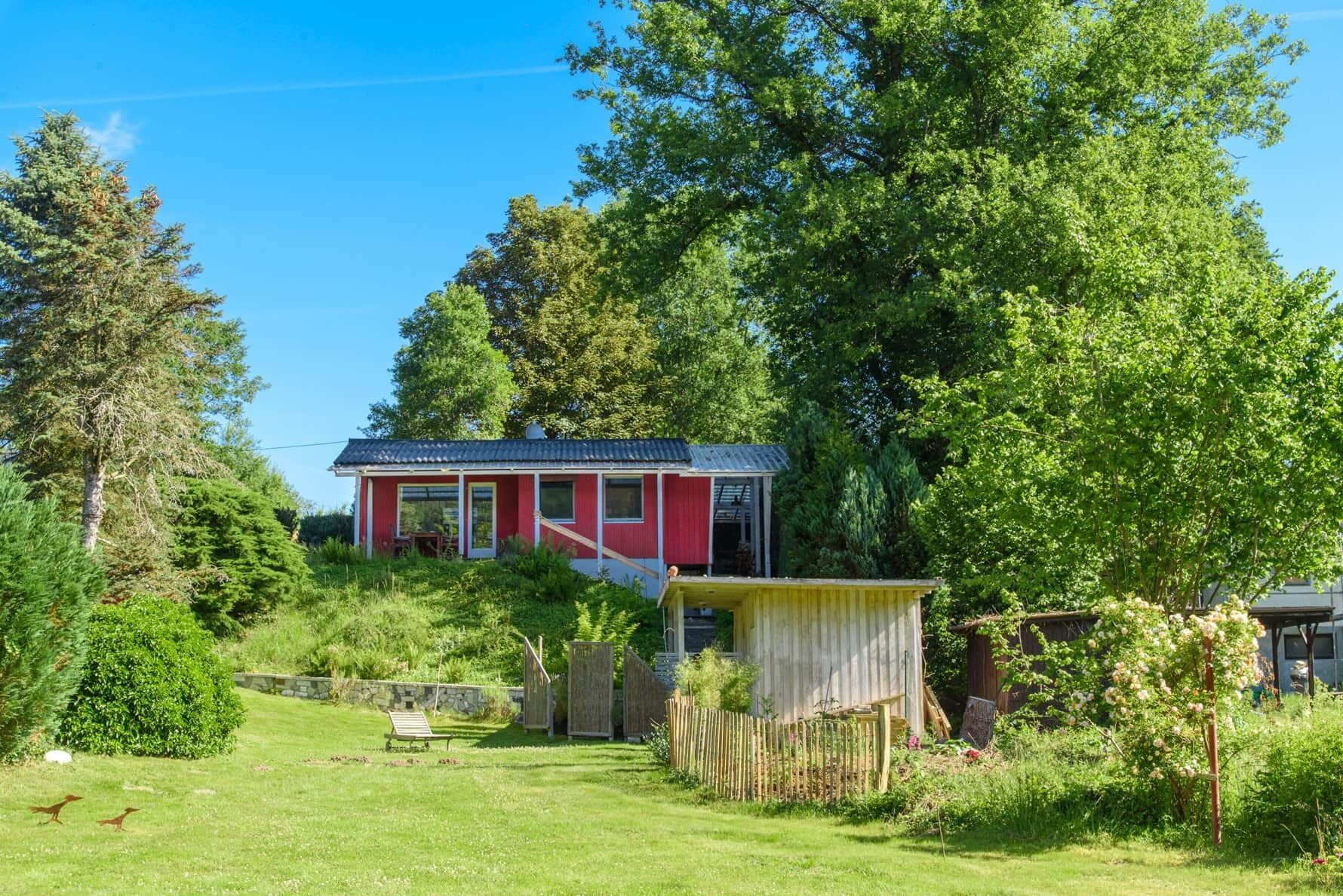 Una casa roja con jardín y valla de madera.