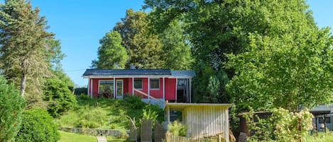 Una casa roja con jardín y valla de madera.