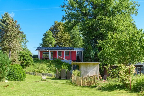 Une maison rouge avec un jardin et une clôture en bois.