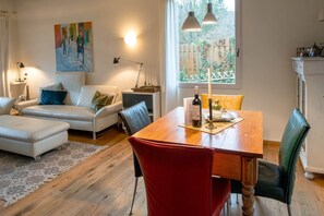 A modern living room with a wooden dining table, a sofa, and a painting on the wall.
