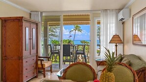A room with a wooden cabinet, a glass table with fruits, wicker chairs, and a view of the ocean. - Islander on the Beach ONE-BEDROOM unit #308, Top floor, incredible Ocean Views (Kapaʻa)