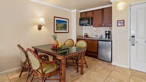 A compact kitchen with a dining area, featuring a microwave, stainless steel dishwasher, and a tiled backsplash. - Islander on the Beach ONE-BEDROOM unit #308, Top floor, incredible Ocean Views (Kapaʻa)