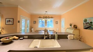 A kitchen with a central island, a sink, and a dining area with chairs. - Dragonfly-Private Setting w/ Easy Beach Access; Covered & Screened Porch;TV/WiFi (Edisto Beach)