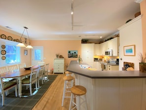 A kitchen with a central island, white cabinetry, and a dining area with a wooden table and chairs.