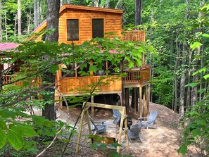 Une cabane en bois dotée d’un balcon, entourée d’arbres.