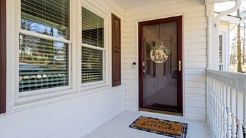A white house with a front door, a welcome mat, and a sign that says "Stay awhile".