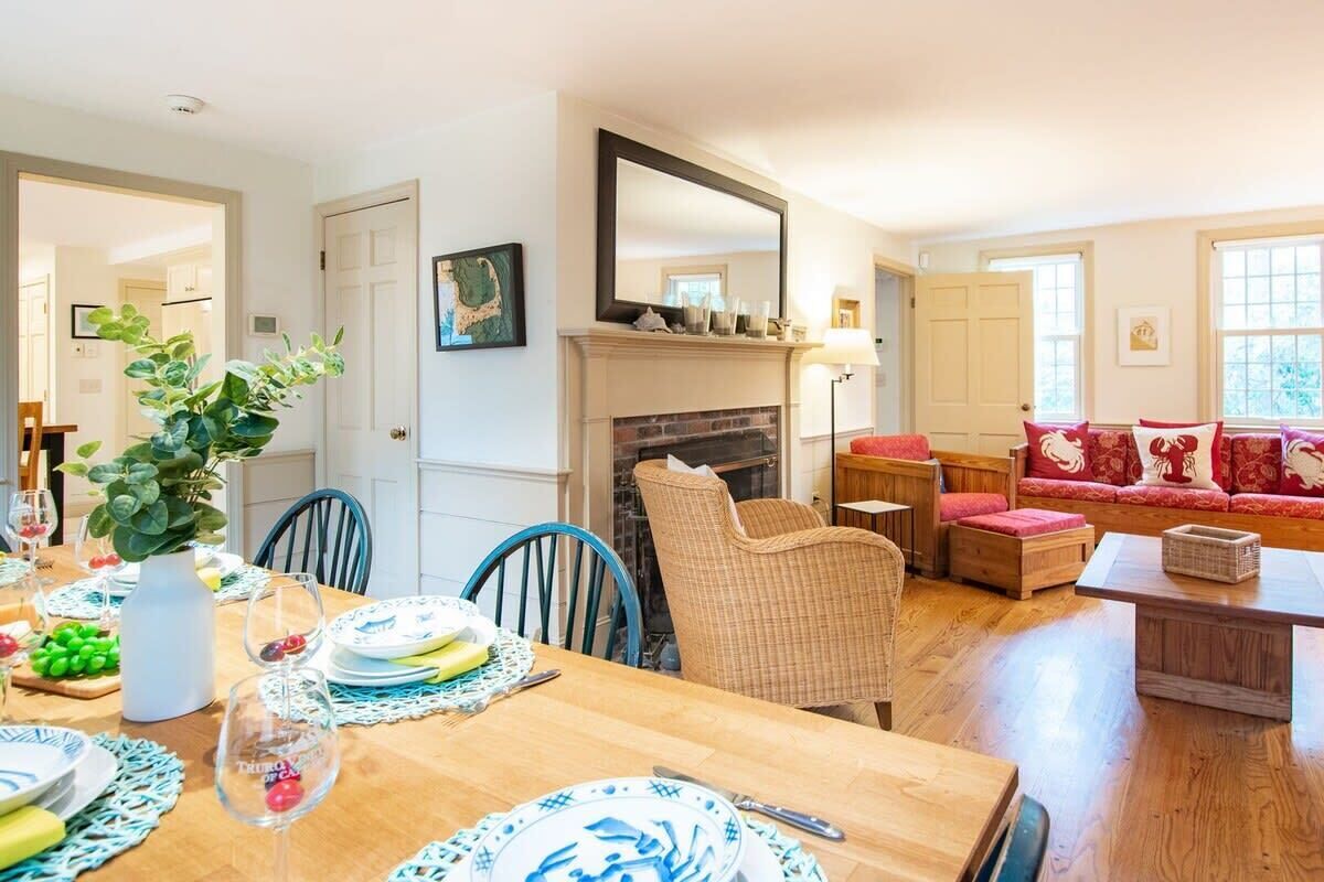 A dining area with a wooden table set for a meal, a fireplace, and a seating area with a sofa and chairs.