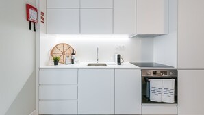 Eine moderne Küche mit weißen Schränken, einem eingebauten Ofen und einer Kaffeemaschine.