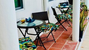 A covered outdoor seating area with tables and chairs, a tiled floor, and potted plants. - The Poolside Pad- 5 mins from airport & beaches (Bon Accord)