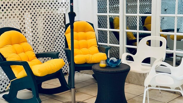 A poolside area with two yellow cushioned chairs, a small round table, and a yellow umbrella. - The Poolside Pad- 5 mins from airport & beaches (Bon Accord)