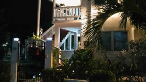 A two-story building with a balcony on the upper floor, a gated entrance, and a staircase leading to the second floor. - The Poolside Pad- 5 mins from airport & beaches (Bon Accord)