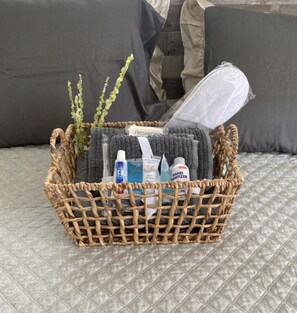 A wicker basket containing toiletries on a bed with a quilted cover. - Near Beach (Oistins)