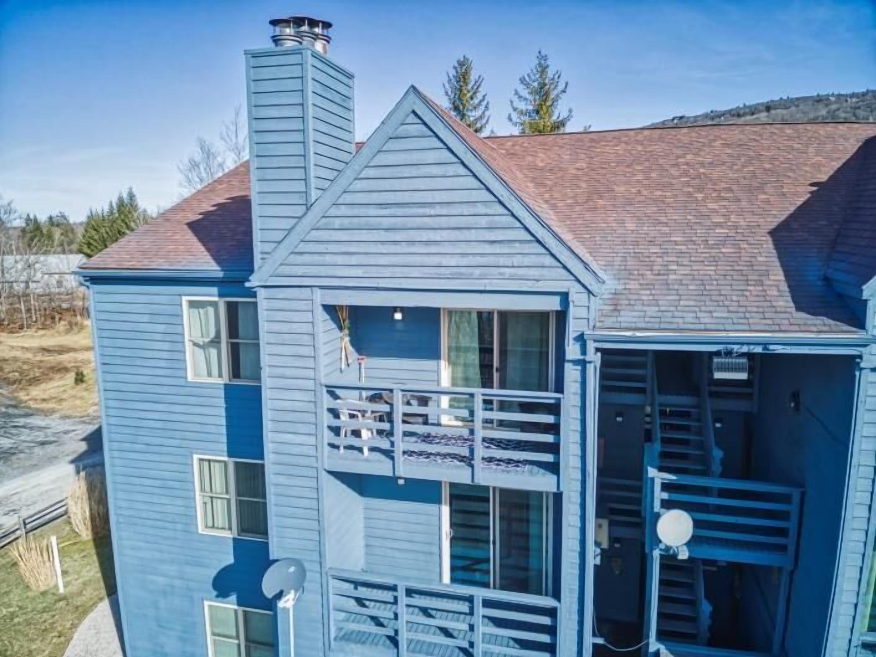 A two-story blue house with a chimney, a balcony, and a garage.