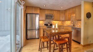 Una cocina moderna con armarios de madera, electrodomésticos de acero inoxidable y una mesa de comedor de vidrio.